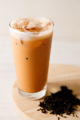 Iced Thai milk tea in a glass on wooden table.