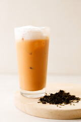 Iced Thai milk tea in a glass on wooden table.