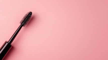 Black mascara wand on a pink background with Copy Space for cosmetic advertising or beauty product presentation.