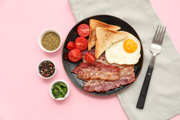 Plate with tasty fried egg, bacon, toasts, tomatoes and spices in bowls on pink background. Top view