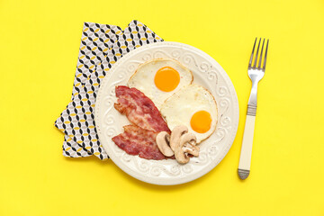 Plate with tasty fried eggs, bacon and mushrooms on yellow background. Top view