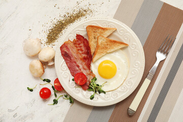 Plate with fried egg, bacon, toasts and mushrooms on white grunge background. Top view