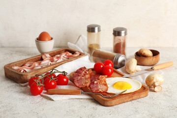 Board with fired egg, bacon, tomatoes, mushrooms and jars of spices on table against white background