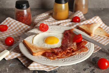 Plate with fired egg, bacon, tomatoes and jars of spices on grey background