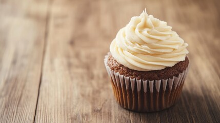 Delicious cupcake with creamy frosting on rustic wooden table with ample copy space.