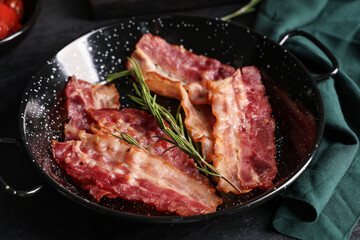 Frying pan with tasty fried bacon on table