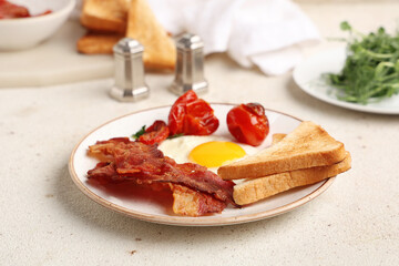Plate with fried egg, bacon, toasts and dried tomatoes on white background