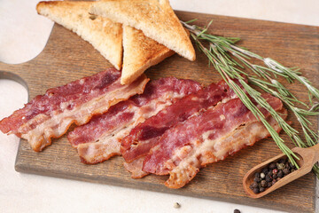 Fried bacon, toasts, rosemary and scoop of pepper on cutting board