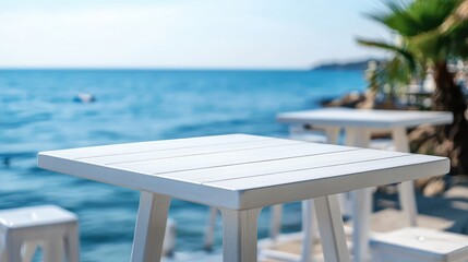 Fototapeta premium White Wooden Table on Bar Counter Against Blurred Blue Sea Background and Green Palm Fronds in Bright Sunlight