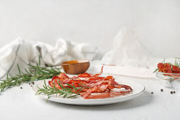 Plate with fried bacon rashers and rosemary on white background