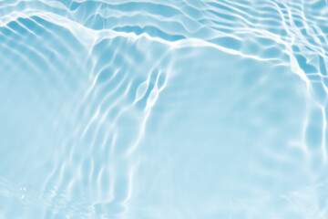 Blue water with ripples on the surface. Defocus blurred transparent blue colored clear calm water surface texture with splashes and bubbles. Water waves with shining pattern texture background.