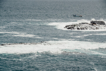 The surface of the dark blue water ripples with small waves and rocks.
