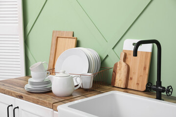 Holder with clean dishes near sink on counter in kitchen