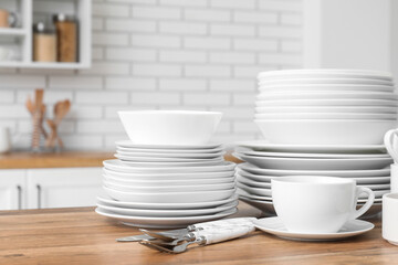 Clean white dishes and cutlery on counter in kitchen