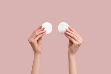 Female hand with cotton pads on beige background