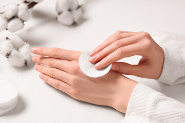 Cotton flowers and female hands with cotton pads on white background, closeup