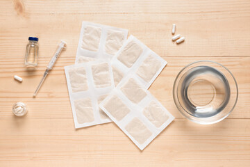 Mustard plasters with medicines and bowl of water on wooden background