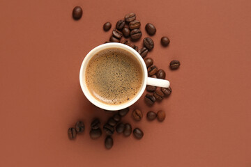 Cup of hot coffee and beans on brown background