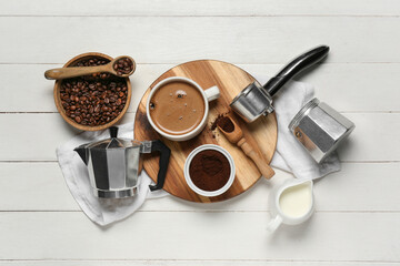 Geyser coffee maker with cup, portafilter, jug of milk and beans on white wooden background