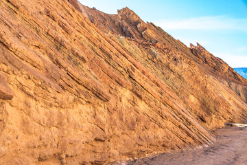 A rocky hillside with a blue sky in the background
