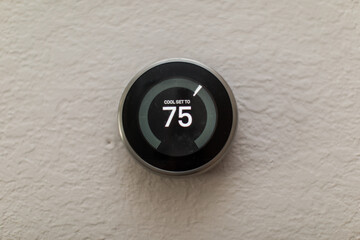 Nest Generation Electric Round Thermostat set to 75 degrees in the house