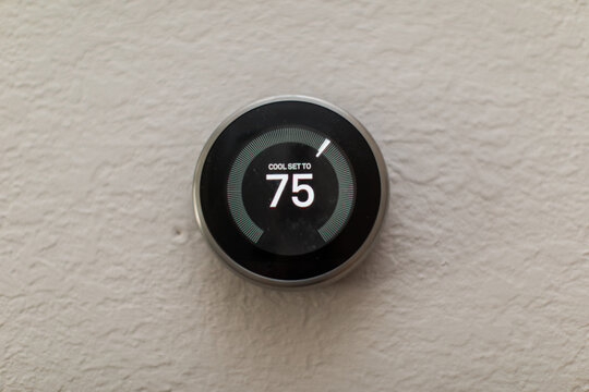Nest Generation Electric Round Thermostat set to 75 degrees in the house