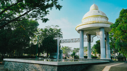 White monument building with a distinct yellow dome in a park. © Kholis