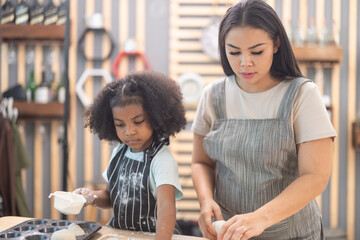 Mother and child engaged in baking activity together in a cozy kitchen interior during daylight...