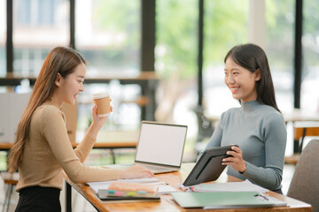 Two Asian business women discuss and discuss company paperwork. in the office room