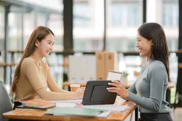 Fototapeta premium Two Asian business women discuss and discuss company paperwork. in the office room