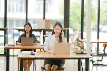 Two Asian business women discuss and discuss company paperwork. in the office room