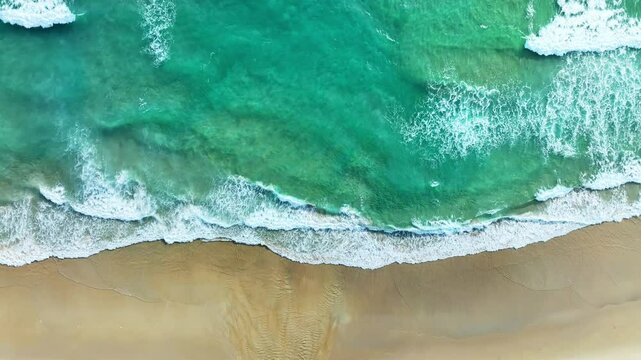 Drone shot top view above an empty beach,Amazing sea water and waves crashing on sandy shore,Top down view over ocean nature beach background