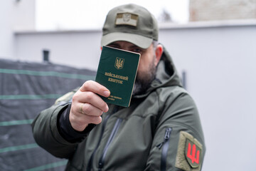 A man in a military uniform holds a military registration document (military ID, card)....