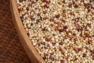 Close-up of mixed quinoa grains in a wooden bowl, featuring white, red, and black quinoa seeds. Ideal for healthy food and nutrition projects