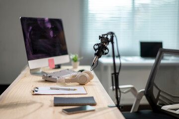 A desk with a computer monitor, a keyboard, a pen, a notebook, a cell phone
