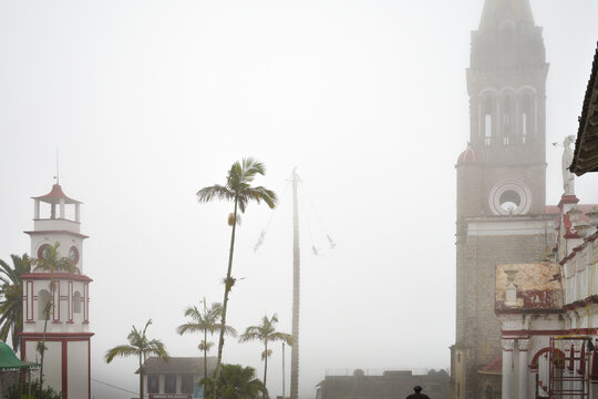 Center and Church of Cuetzalan covered with fog and Cuetzalan flyers or voladores de Papantla descending through the fog