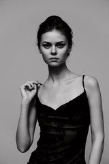 Fototapeta premium Elegant woman in black dress posing confidently against a monochrome background, showcasing beauty and grace. Fashion and portrait photography concept.