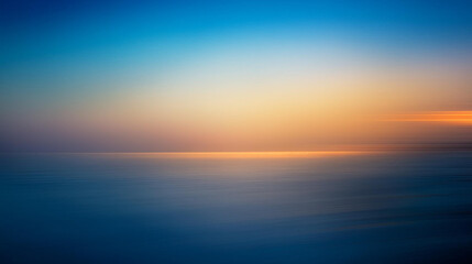 Fototapeta premium Soft gradient sunset over a calm ocean with blurred reflections.