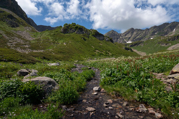 The valley of the Malaya Dukka River on the slopes of the Arkasar ridge in the North Caucasus and the tourist trail to the Dukka Lakes on a sunny summer day, Arkhyz, Karachay-Cherkessia, Russia