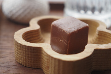 A delicious chocolate cube elegantly placed in a wooden tray on the table
