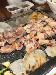 Grilled samgyeopsal, thick slices of pork belly with a perfect balance of crispy edges and tender meat. Served with lettuce, garlic, and dipping sauces for a classic Korean barbecue experience.
