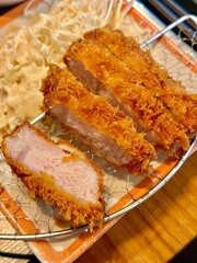 Crispy tonkatsu, a Japanese-style breaded and deep-fried pork cutlet, served with shredded cabbage and drizzled with savory sauce. A delightful balance of crunchy texture and juicy meat.
