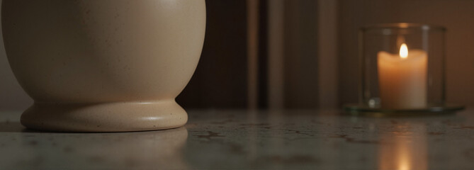 Human funeral urn beside burning candle on marble table