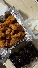 Deep fried chicken wing with garlic sauce in Korean style serve with kimchi and pickled radish in top view on wooden table for asian food concept.
