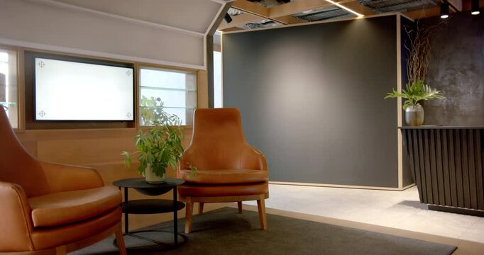 Modern office lobby with leather chairs, plants, and reception desk, copy space
