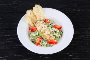 Caesar salad with chicken on a black background