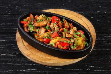Ojakhuri. Stewed meat with vegetables and herbs on a black background