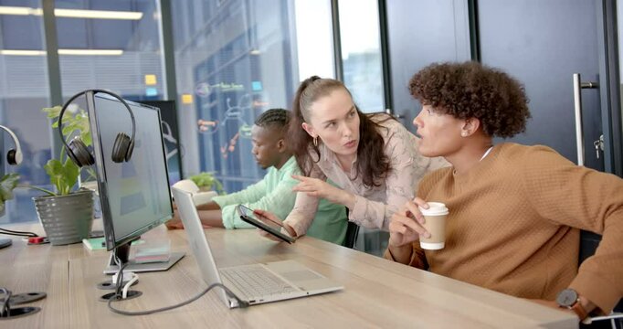 Collaborating in office, diverse team discussing project using laptop and tablet