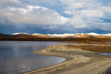 Russia. Magadan Region. Beautiful Lake Momontay against the backdrop of a snowy mountain range. Late autumn in the vicinity of Lake Momontay.