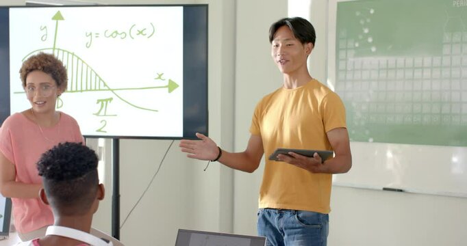 Presenting math project, students using tablet and whiteboard in high school classroom